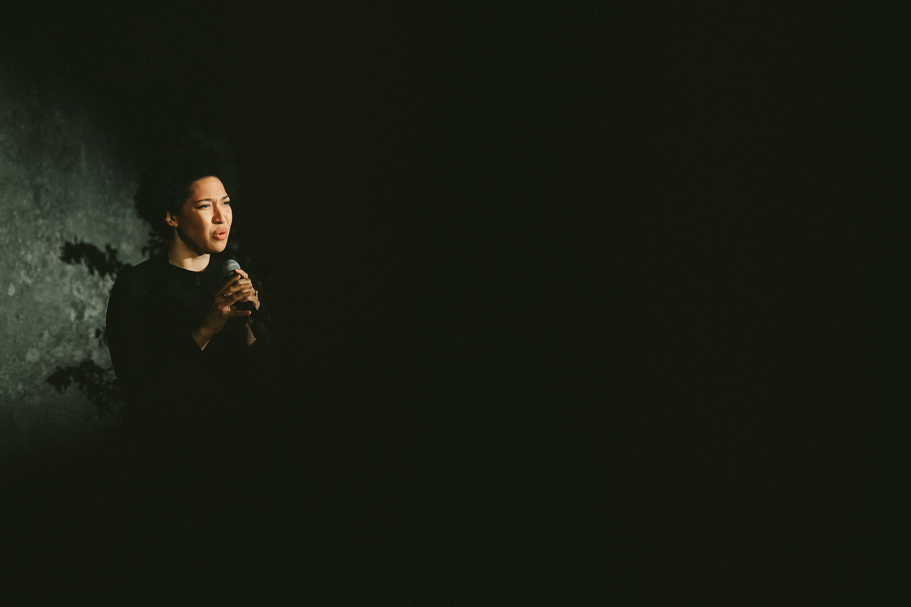 A dark image of Julia singing with a look of intensity.
