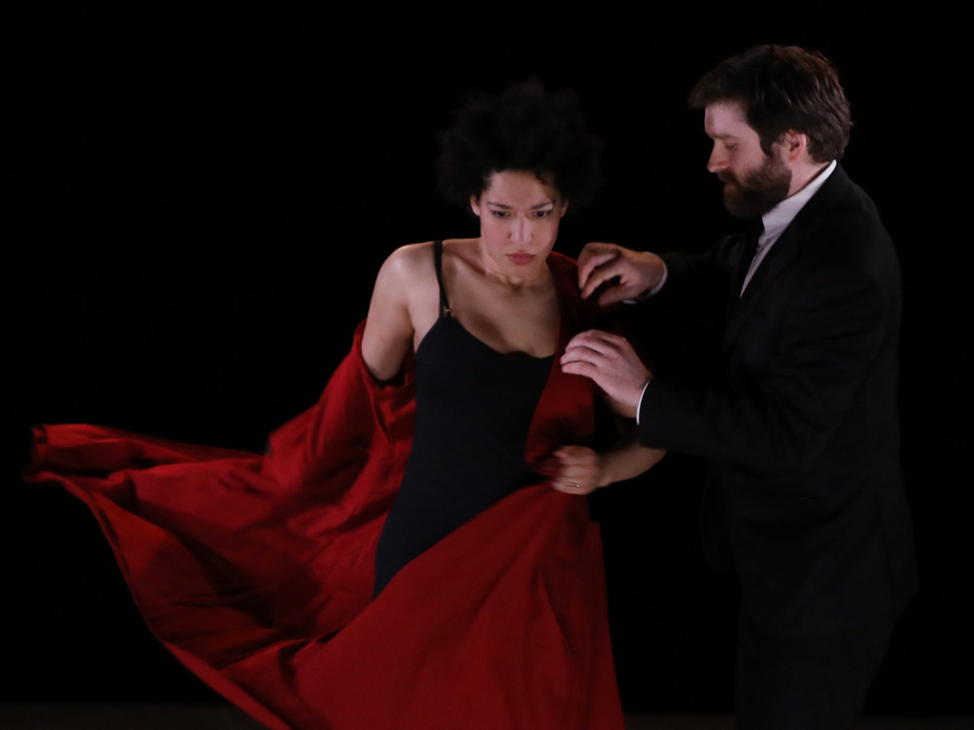 Julia Bullock stands beside a man who is removing a red jacket from her.